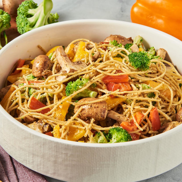 ['A bowl of pasta with broccoli, mushrooms, and bell peppers.']