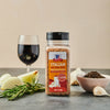 A bottle of McCormick Italian Red Wine Style Seasoning with a glass of red wine onions garlic rosemary and black peppercorns.