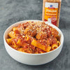 A bowl of pasta with meatballs and marinara sauce topped with parmesan cheese next to a McCormick Italian Red Wine Style Seasoning jar.