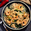 A bowl of rice noodles with shrimp bok choy and spices.