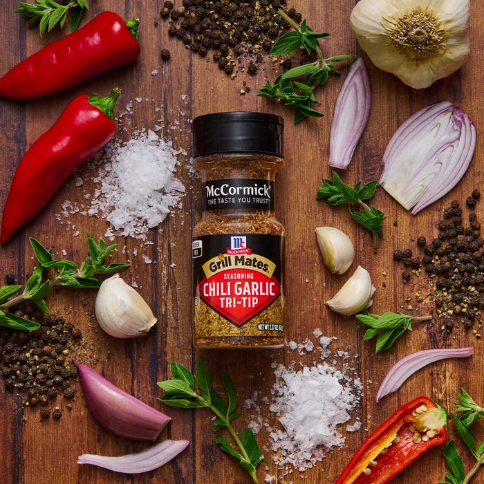 A bottle of McCormick Grill Mates Chili Garlic Tri-Tip seasoning with red peppers garlic onions salt and peppercorns.