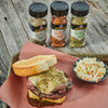 ['McCormick Grill Mates seasoning jars with a roast beef sandwich and coleslaw.']