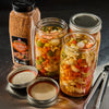 ['A jar of McCormick Grill Mates Fiery Habanero &amp; Roasted Garlic seasoning next to three jars of pickled vegetables.']