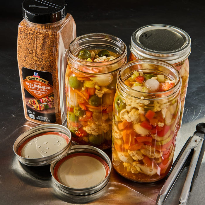 ['A jar of McCormick Grill Mates Fiery Habanero &amp; Roasted Garlic seasoning next to three jars of pickled vegetables.']
