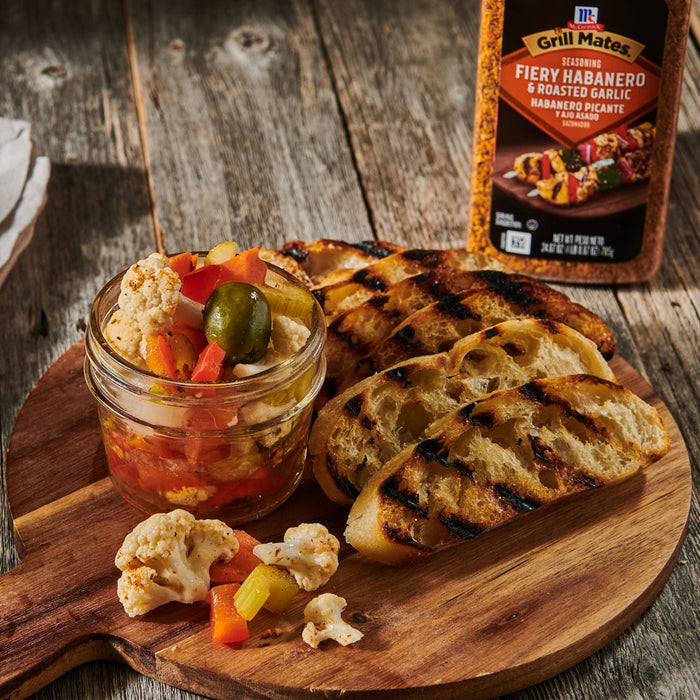 ['A jar of pickled vegetables, grilled bread, and a bottle of Grill Mates Fiery Habanero &amp; Roasted Garlic seasoning.']