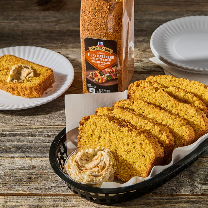 ['McCormick Grill Mates Fiery Habanero &amp; Roasted Garlic seasoning with a basket of cornbread and a small container of butter.']