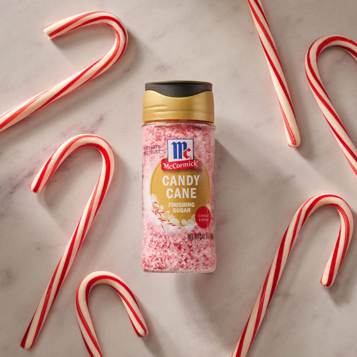 A container of McCormick Candy Cane Cinnamon Flavored Crunch Toppings is surrounded by candy canes.