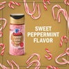 A jar of McCormick Candy Cane Seasoning is surrounded by candy canes, highlighting its sweet peppermint flavor.