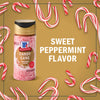 A jar of McCormick Candy Cane Seasoning is surrounded by candy canes, highlighting its sweet peppermint flavor.