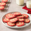 Two festive cocktails with red-sprinkled rims are displayed alongside pieces of white chocolate bark and a McCormick brand sprinkles container.