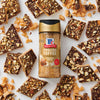 A jar of McCormick English Toffee seasoning is surrounded by pieces of toffee bark.