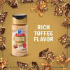 A bottle of McCormick English Toffee Seasoning is surrounded by pieces of toffee, highlighting its rich toffee flavor.