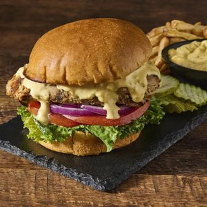 A juicy burger with lettuce, tomato, onion, and a creamy sauce on a toasted bun.