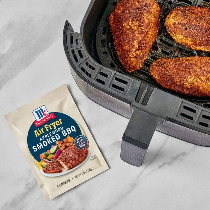 McCormick Air Fryer Sweet &amp; Smoky BBQ seasoning mix is shown next to an air fryer with seasoned chicken inside.