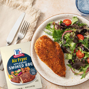 A plate with air fried chicken seasoned with McCormick Air Fryer Smoky BBQ seasoning, accompanied by a fresh salad.