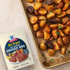 A package of McCormick Air Fryer Smoked BBQ seasoning is displayed next to a sheet pan of seasoned and cooked potatoes.