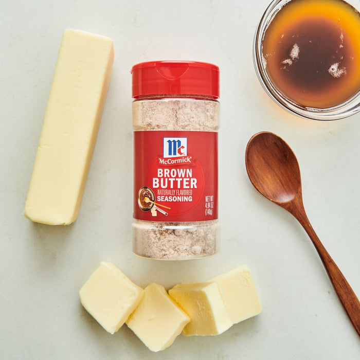 ['A jar of McCormick Brown Butter Seasoning with butter sticks and a bowl of melted butter.']