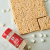 ['A container of McCormick Brown Butter seasoning next to a plate of rice crispy treats.']