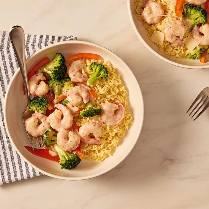 An overhead view of two bowls of creamy shrimp and orzo pasta with broccoli and red peppers, a delicious meal prepared with Mccormick Lemon Herb Butter All Purpose Sauce Mix Envelope .87 Oz.