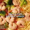 A close-up shot shows a creamy sauce made from the Mccormick Lemon Herb Butter All Purpose Sauce Mix Envelope .87 Oz drizzled over a delicious meal of shrimp, steamed vegetables, and orzo pasta.