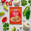 A packet of McCormick Street Taco Chicken Taco seasoning is surrounded by fresh ingredients like limes, peppers, garlic, and cilantro.