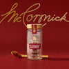 A glass jar of Mccormick Gourmet Saffron 0.035 Oz is displayed on a red background, with a golden spoon holding saffron threads beside it and the McCormick logo in gold script above.