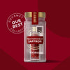 A clear jar of Mccormick Gourmet Saffron 0.035 Oz, part of the Our Best Collection, contains vibrant red saffron threads and is topped with a gold cap, set against a rich red background.