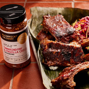 ['A jar of McCormick Culinary Tamarind &amp; Pasilla Chile Seasoning sits next to a plate of ribs.']
