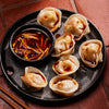 ['A plate of dumplings with a side of chili oil.']