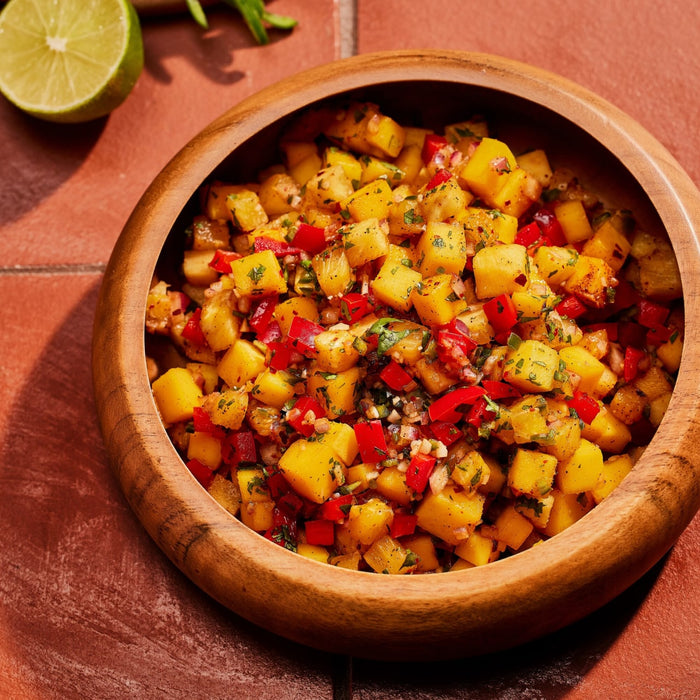 ['A wooden bowl filled with a colorful mango salsa.']