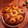 ['A close-up of a pineapple upside-down cake with a cherry on top of each pineapple slice.']
