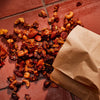 ['A brown paper bag spills out a variety of roasted nuts and seeds.']