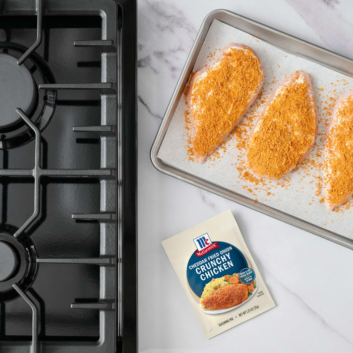 A packet of McCormick Shake n Bake is displayed next to a baking sheet with chicken breasts coated in breading, ready to be cooked.