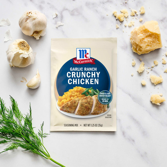 A packet of McCormick Garlic Ranch Crunchy Chicken mix is displayed with garlic, parmesan cheese, and dill sprigs.