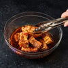 A bowl of meat marinating in McCormick Grill Mates Asian BBQ sauce, ready to be cooked.