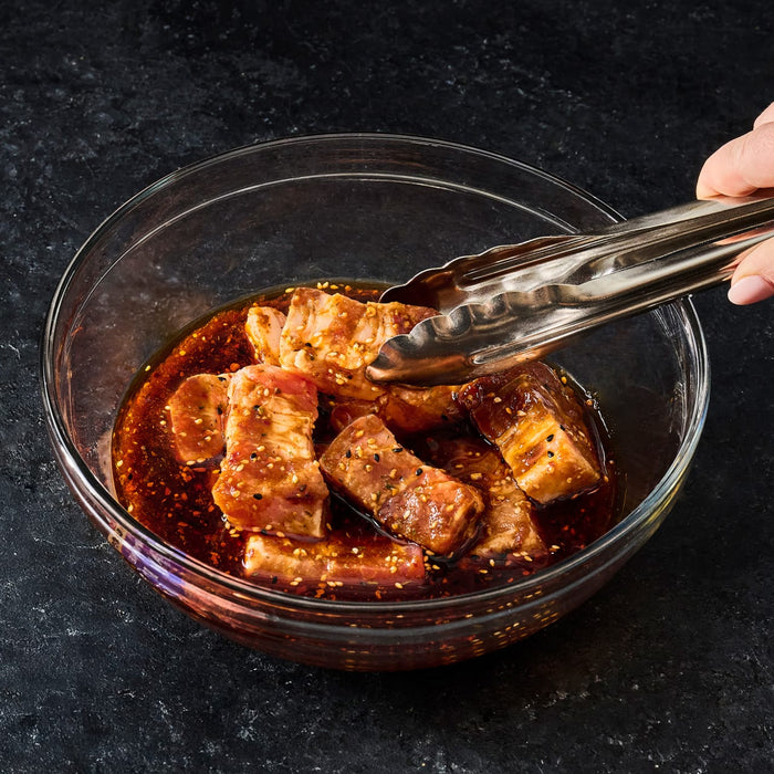 A bowl of meat marinating in McCormick Grill Mates Asian BBQ sauce, ready to be cooked.