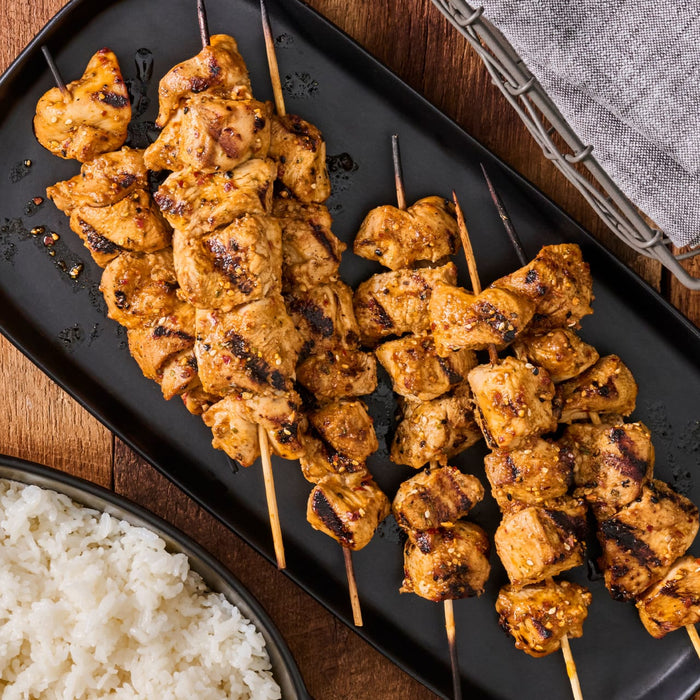 A plate of grilled chicken skewers with rice, showcasing a delicious and visually appealing meal.