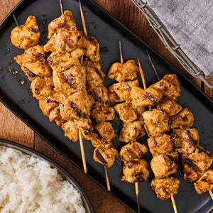 A plate of grilled chicken skewers with rice showcasing a delicious and visually appealing meal.