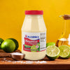 A bottle of McCormick Mayonesa with lime juice next to limes and salt on a wooden table.
