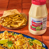 A jar of McCormick Mayonesa with a bowl of corn salad with lime wedges and cilantro.