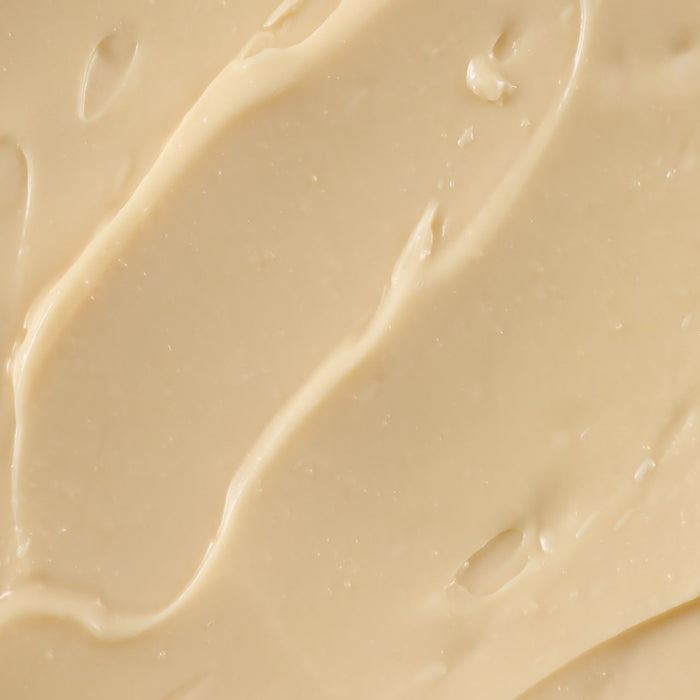 ['A close-up of a creamy, beige substance, possibly a lotion or moisturizer.']