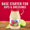['A jar of McCormick Mayonesa with lime slices on a wooden surface.']
