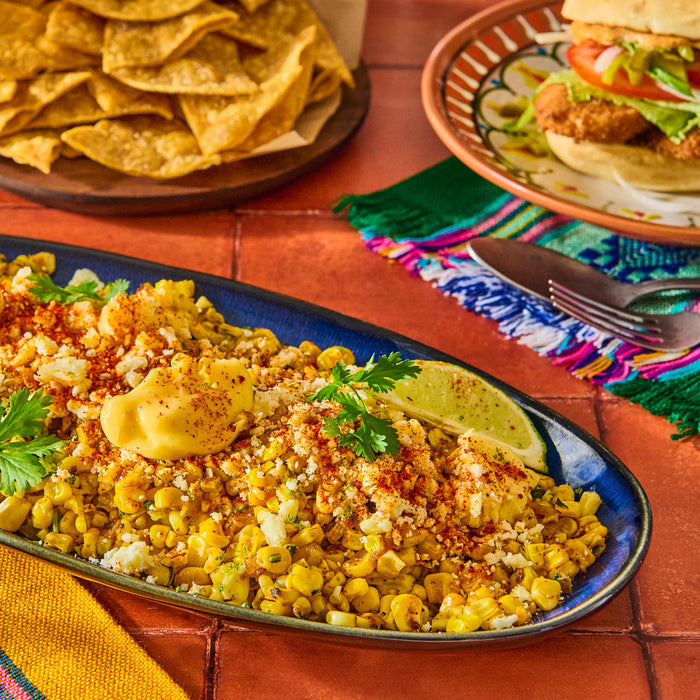 ['A plate of Mexican street corn with cotija cheese, chili powder, and lime.']