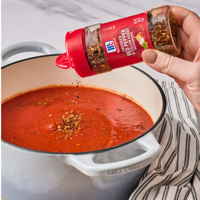 ['A hand sprinkles McCormick Crushed Red Pepper &amp; Italian Herbs Seasoning into a pot of tomato sauce.']