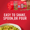 ['A hand holding a McCormick Red &amp; Green Pepper Blend shaker, with red pepper flakes falling into a bowl of guacamole.']
