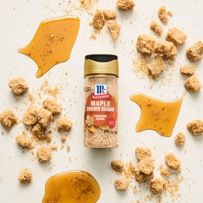 A bottle of McCormick Maple Seasoning is surrounded by maple candy and brown sugar pieces.