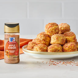 A bottle of McCormick Apple Cider Seasoning sits next to a plate of apple cider-flavored biscuits.