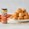 A bottle of McCormick Apple Cider Seasoning sits next to a plate of apple cider-flavored biscuits.