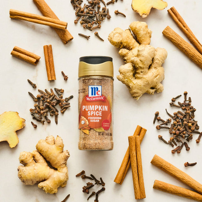 A jar of McCormick Pumpkin Spice is surrounded by cinnamon sticks, cloves, and ginger root.