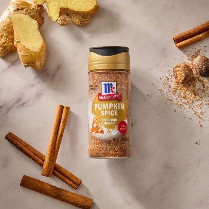 A jar of McCormick Pumpkin Spice is surrounded by cinnamon sticks, cloves, and ginger root.